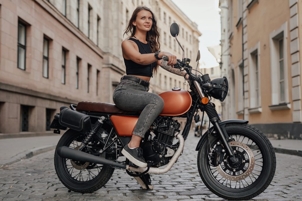 Brown haired woman riding old fashioned motobike outdoors