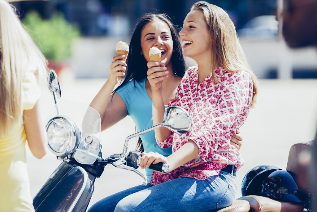 Two teenage girls with motor scooter and ice cream cones