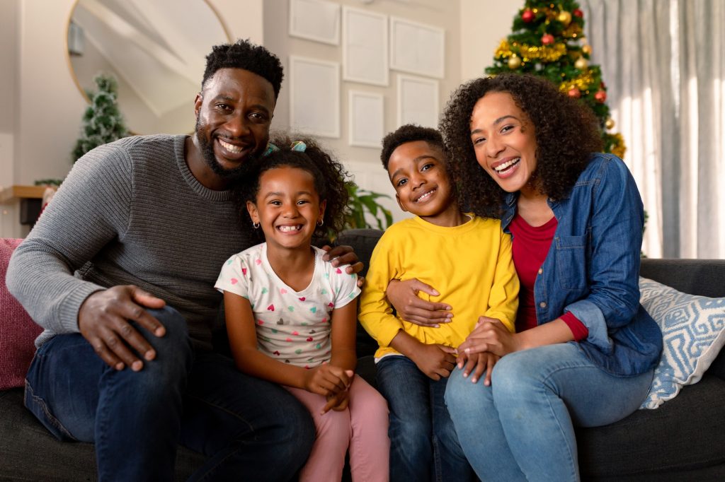 Happy african american family sitting on sofa and looking at camera