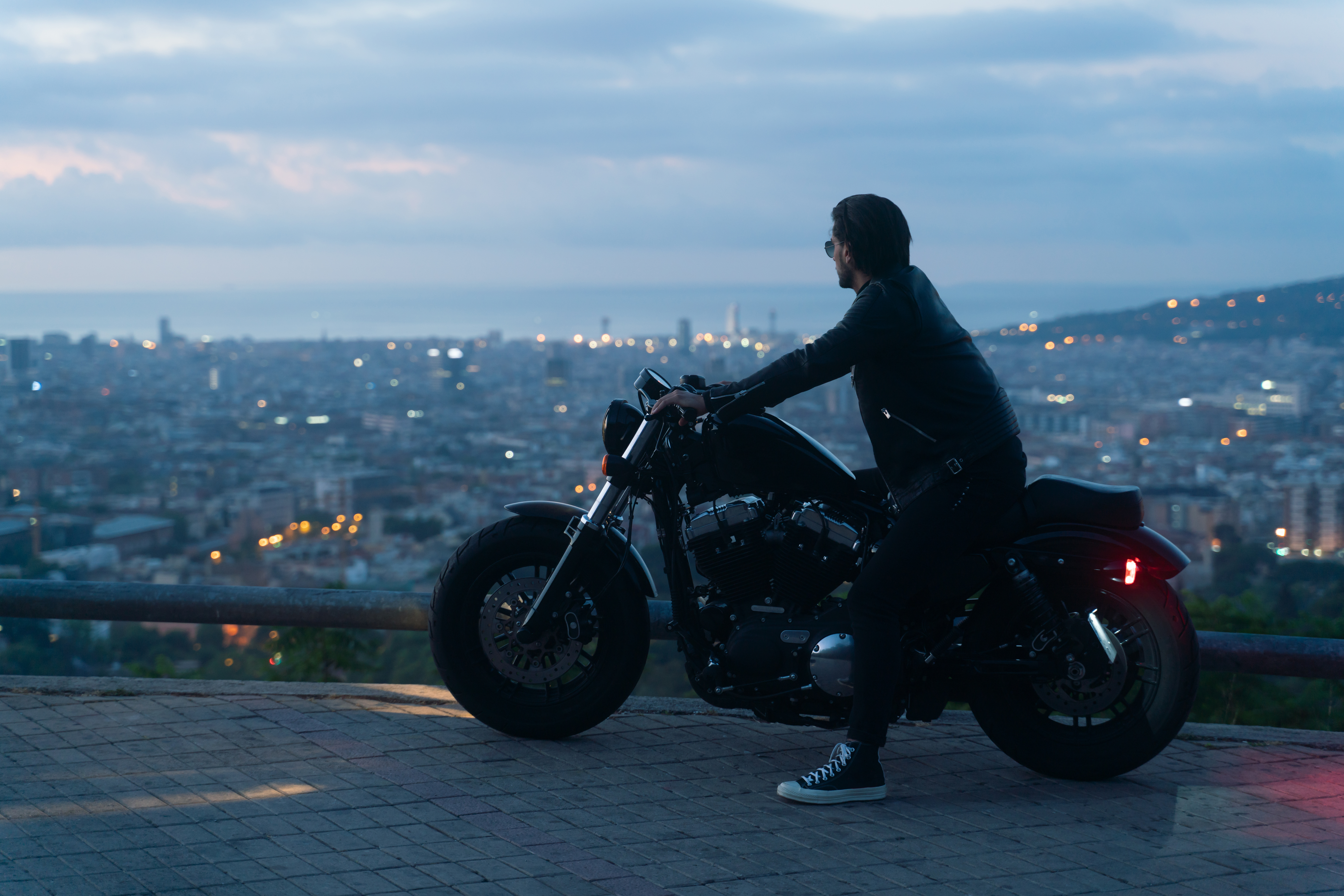 Biker or moto rider after sunset, doing his trip ride with beautiful city views at background