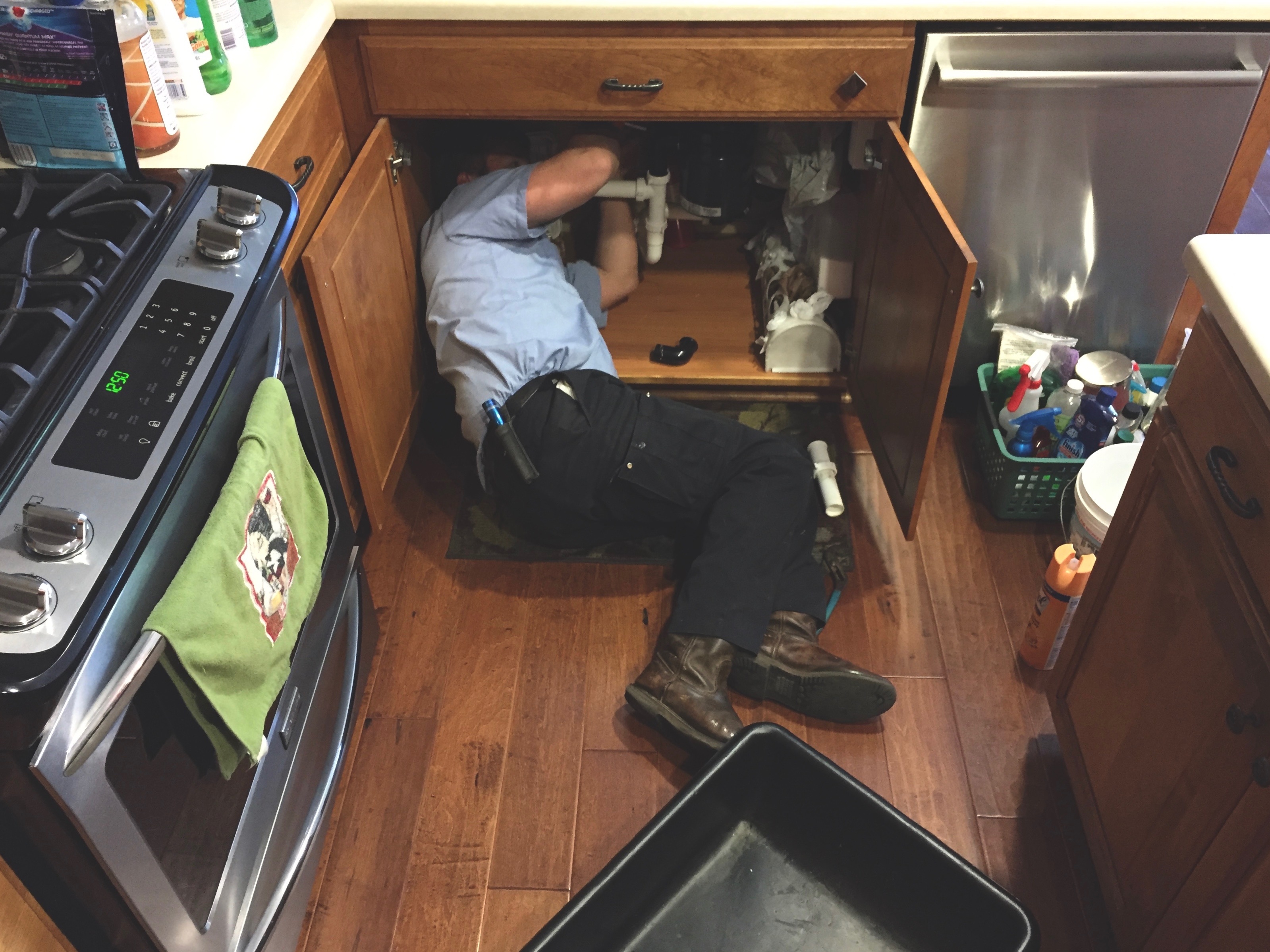 Man working under the kitchen sink fixing the plumbing.
