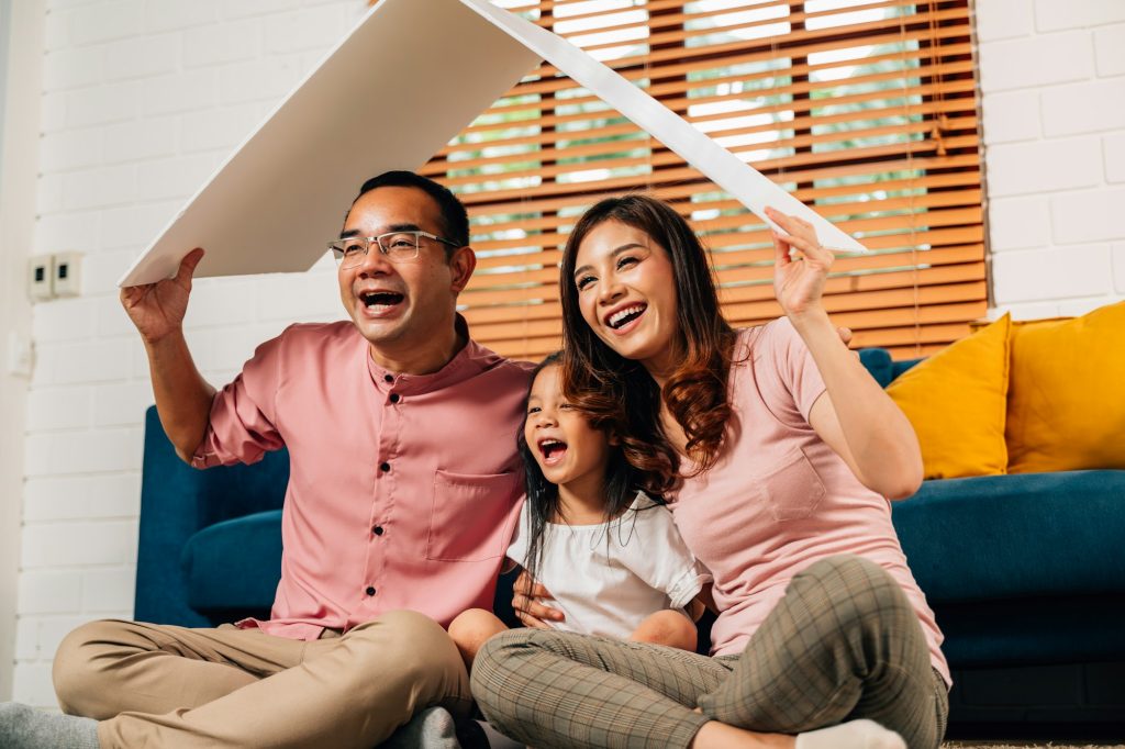 Happy family holding symbolic cardboard roof of life insurance
