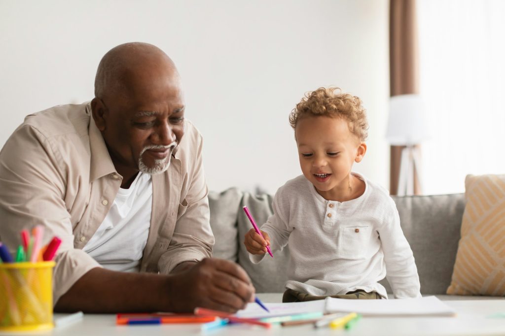 African American Grandfather And Little Grandchild Drawing At Home
