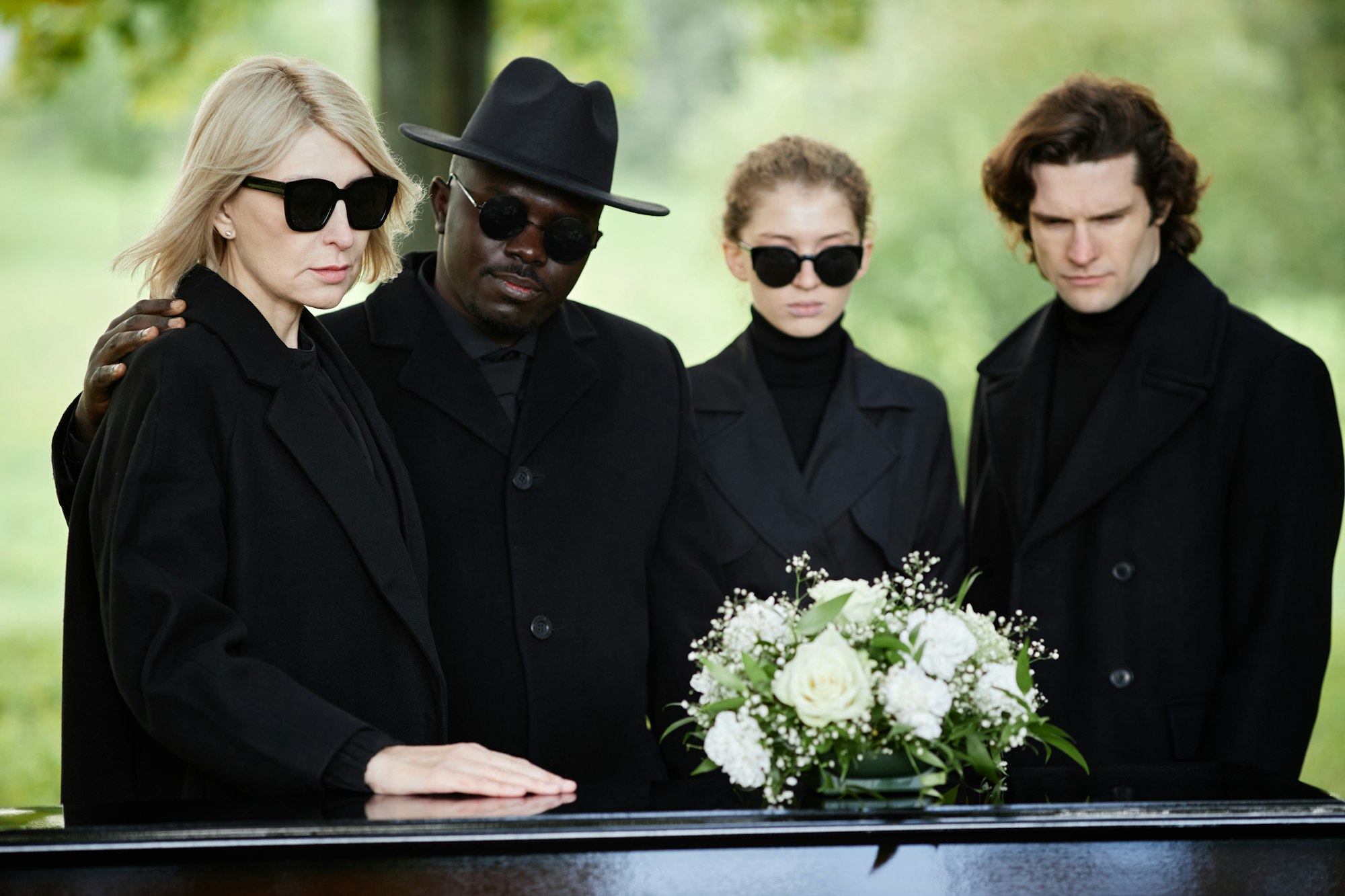 Group of people standing by coffin at outdoor funeral